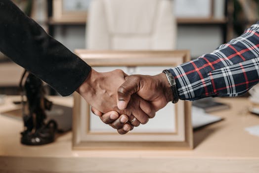 Close-up of a handshake between two professionals in an office environment.
